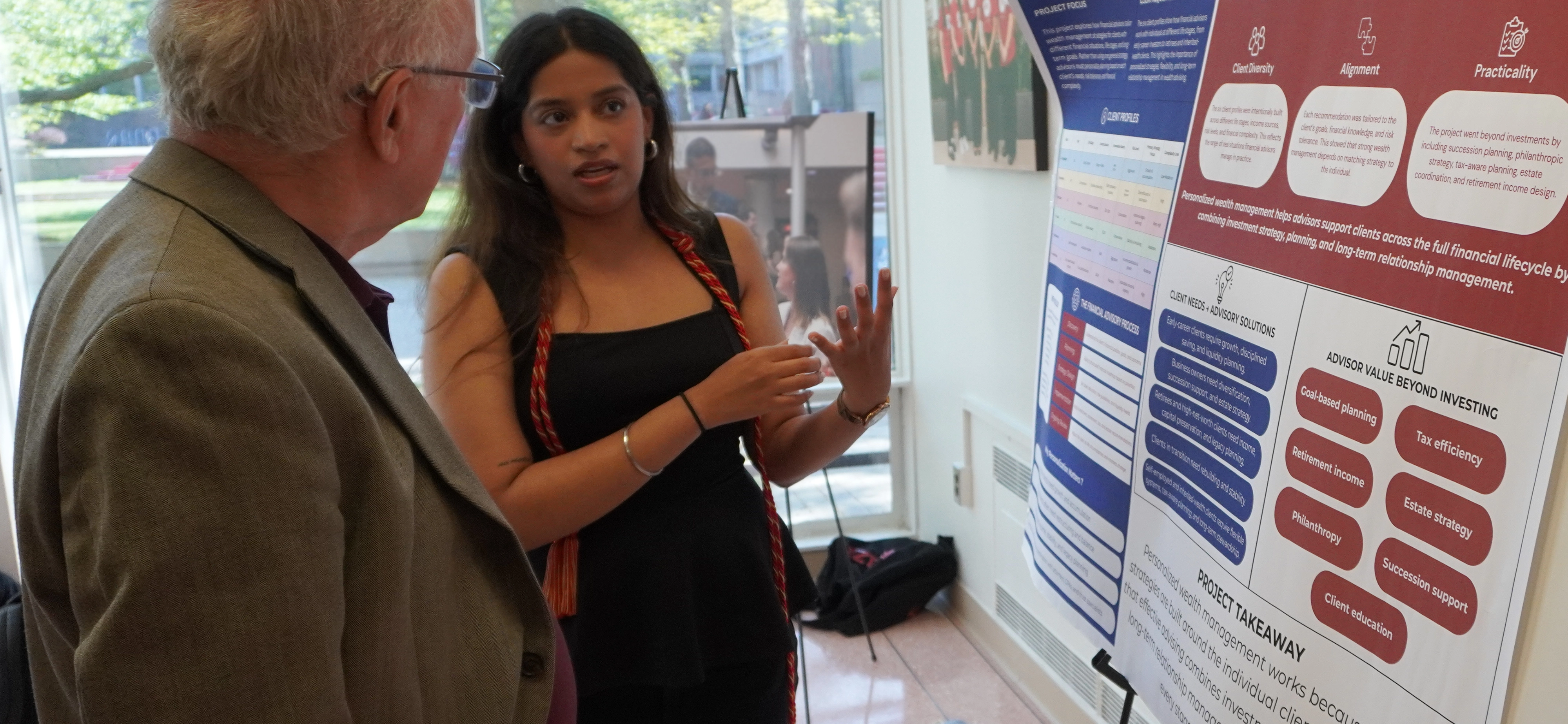student speaking to faculty infront of research board