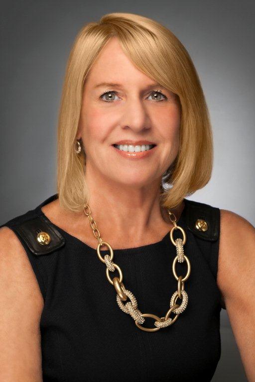 Blonde female wearing a black suit posing in front of grey background