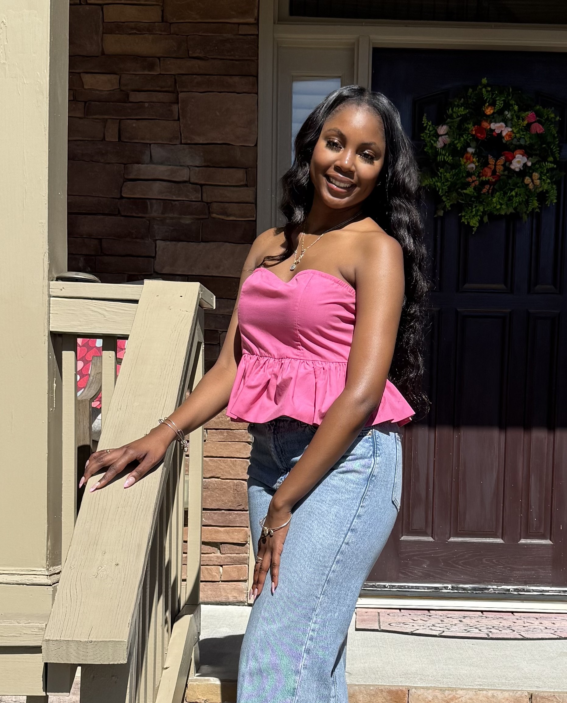 a smiling person stands on the front porch of a house