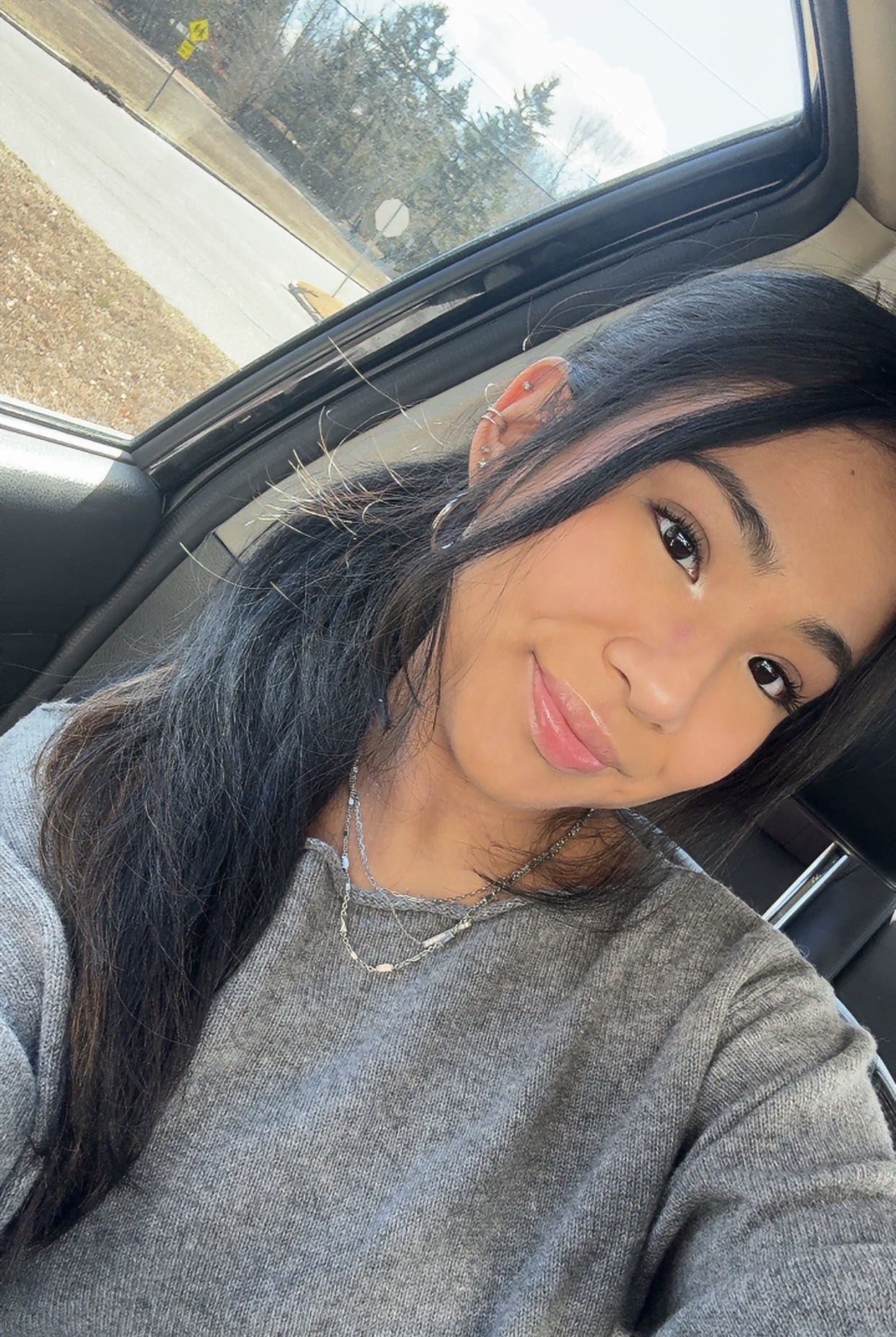 A smiling person takes a selfie while sitting in a car