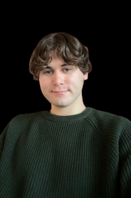 Young man with wavy brown hair wearing a dark green sweater, smiling softly against a black background. 