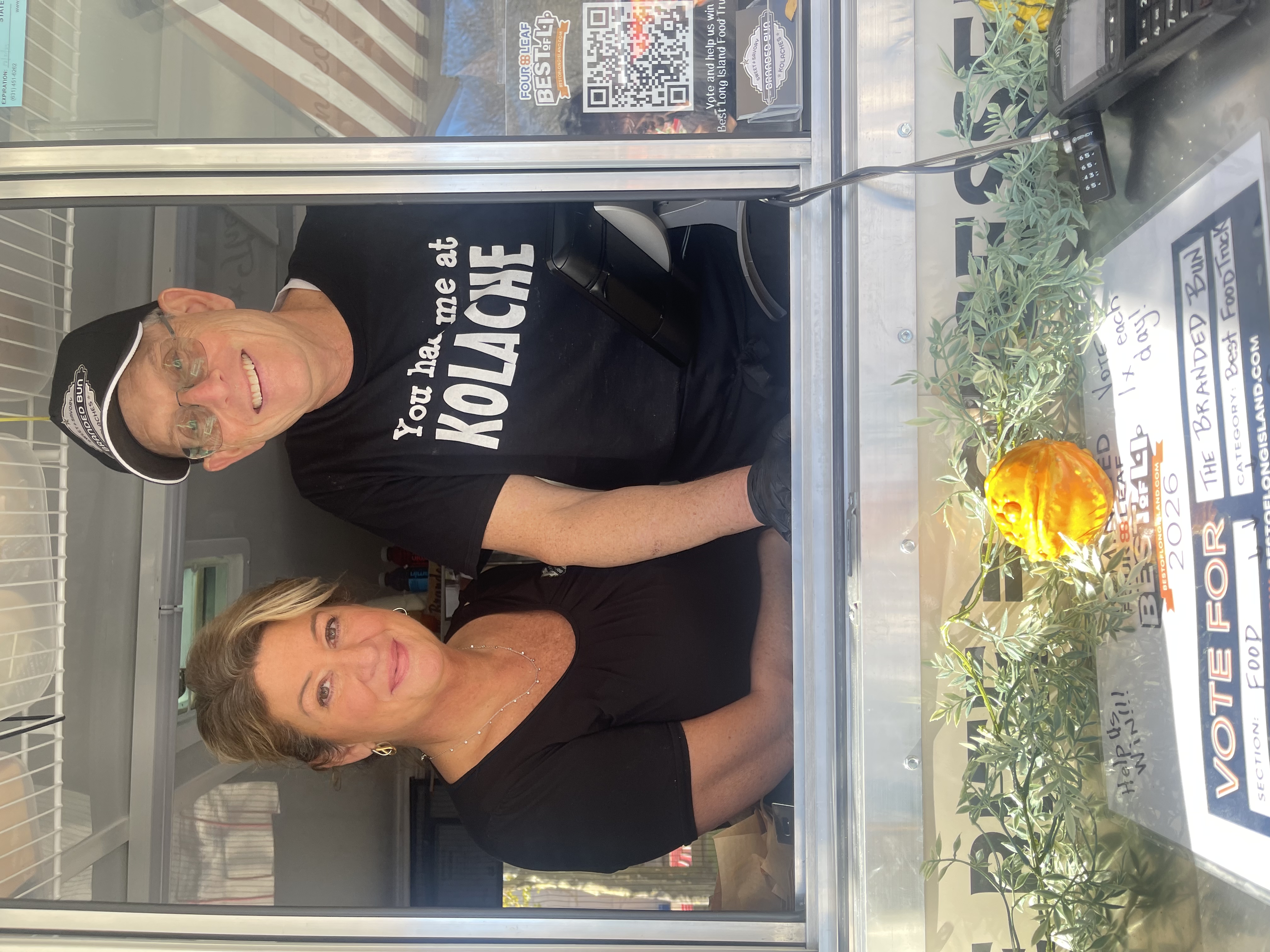 Lynda and Bruce of the Branded Bun smiling from the window inside their truck.